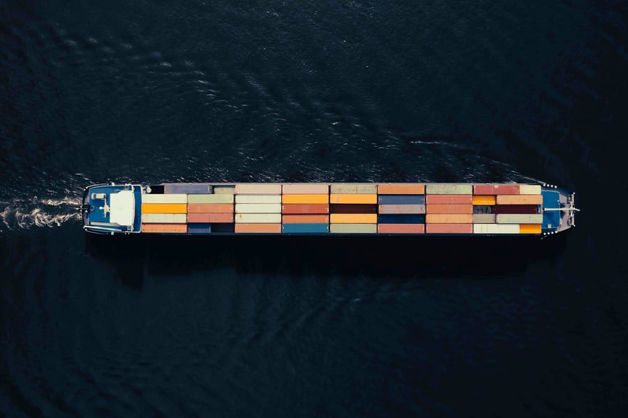 An aerial view of a lone merchant ship at sea carrying cargo