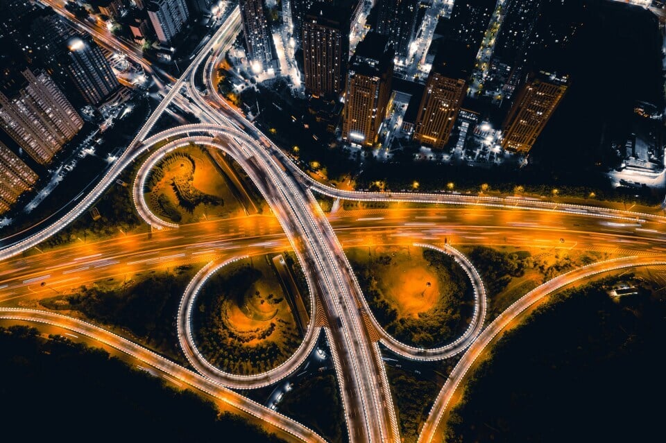 A timelapse aerial night view shot of a motorway junction next to tall buildings