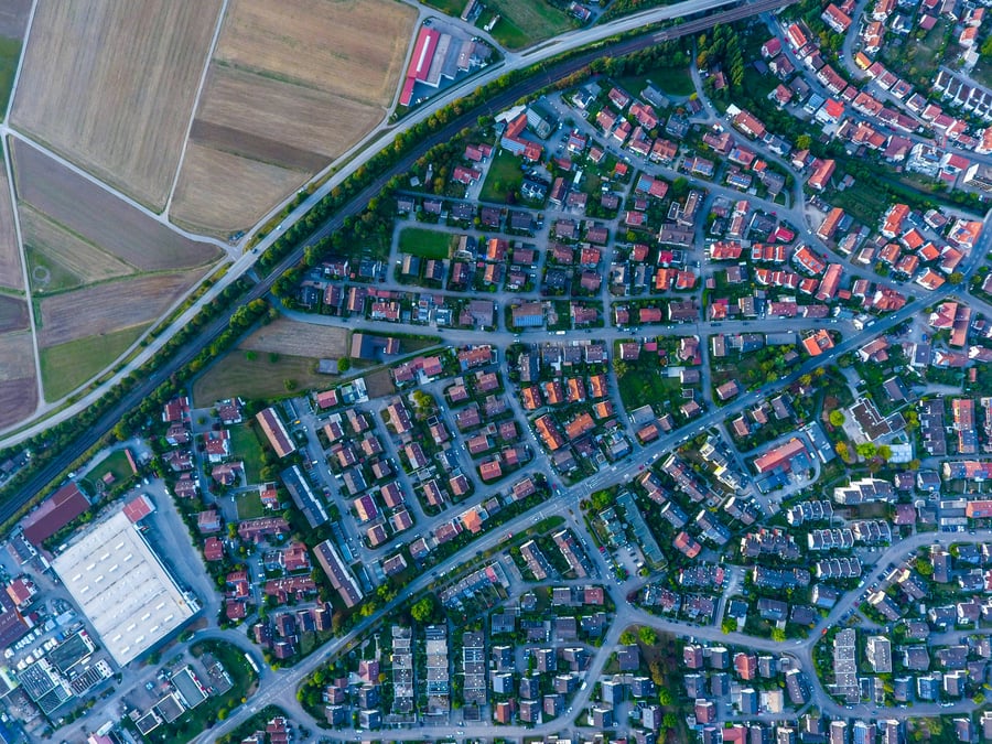 An aerial view of a location that includes houses, farm fields, and an industrial site