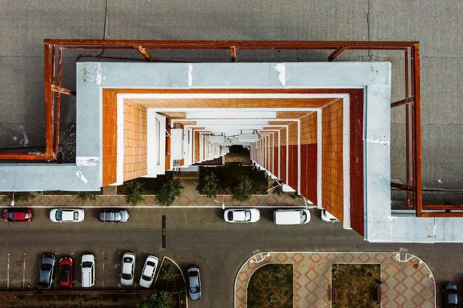 An aerial view of a building facade on a street with parked cars